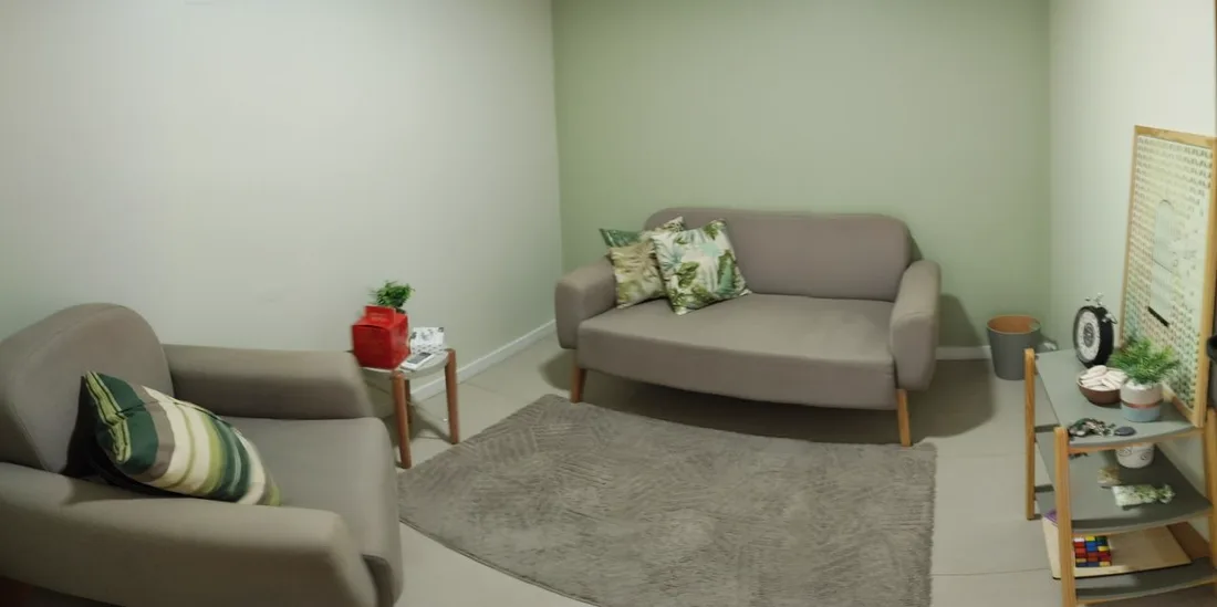 Sala de atendimento com sofá bege, planta e iluminação suave