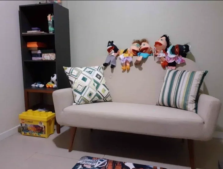 Sala infantil com sofá, brinquedos e fantoches na estante